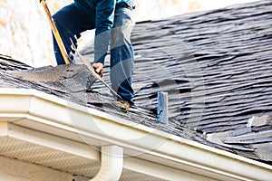 Roofer removing roof nails with roof shingle remover