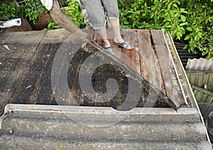 Roofer repair and renovation old asbestos roof. Old house roof with bad wet wooden beams. Roofing construction