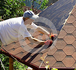 The roofer on the roof cut the tiles with a knife