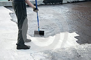 Roofer worker painting bitumen praimer at concrete surface by t