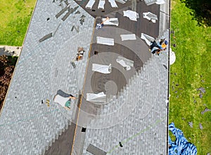 Roofer working on replacement asphalt shingle roof