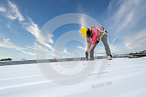 A Roofer working on roof structure of building on construction site, Roofer using electric drill nail gun and installing white