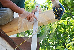 Roofers measuring roof wooden beam installation with measuring tape and spirit level. Roofing construction