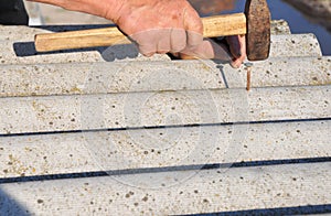 Roofers replace damaged asbestos tile. Repair asbestos roof. Nailing roof shingles. photo