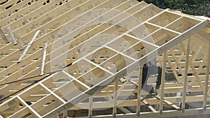 A roofing carpenter works to install the roof of an unfinished house.
