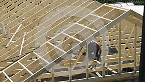 A roofing carpenter works to install the roof of an unfinished house.