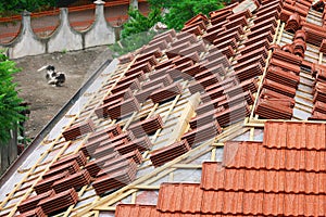 Roofing construction with clay roof tiles. Roofer laying ceramic roof tiles.