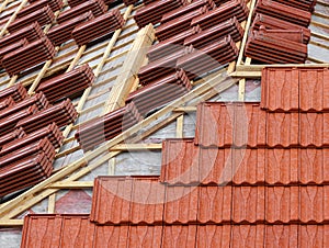 Roofing construction with clay roof tiles. Roofer laying ceramic roof tiles.