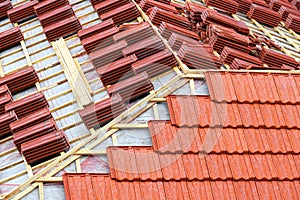 Roofing construction with clay roof tiles. Roofer laying ceramic roof tiles.