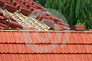 Roofing construction with clay roof tiles. Roofer laying ceramic roof tiles.