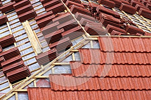 Roofing construction with clay roof tiles. Roofer laying ceramic roof tiles.