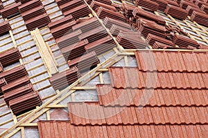 Roofing construction with clay roof tiles. Roofer laying ceramic roof tiles.