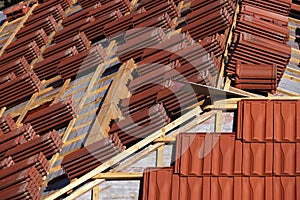 Roofing construction with clay roof tiles. Roofer laying ceramic roof tiles.