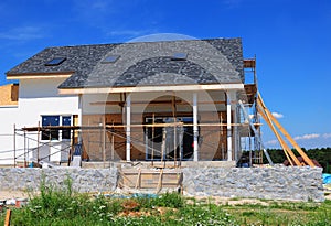 Roofing Construction. House Construction with asphalt shingles roof, skylights, terrace patio.