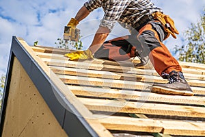 Roofing Contractor Attaching Wooden Elements to the House Roof