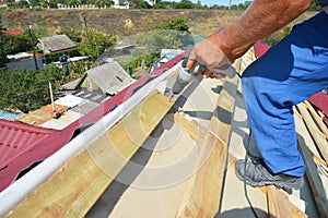 Roofing contractor installing metal roof tile for roof repair. Roofer install metall roof sheets with driver