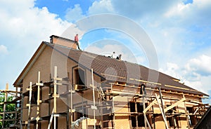 Roofing contractors are finishing installing asphalt roof shingles on the rooftop