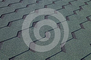 Roofing made of green soft bitumen tiles on a hipped roof of a house. Close up view of Asphalt Roofing green Tile Background.