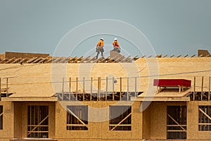 Roofing on roof. Builder roofer install new roof. Construction worker roofing on a large roof apartment building