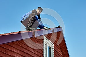 Roofing work in countryside, roofer fixes tin sheets torn off by wind on roofs