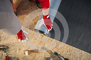 Roofing Worker Installing EPDM Rubber Membrane on Top of Plywood Roof