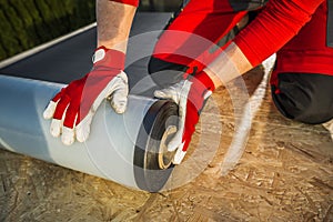 Roofing Worker Preparing a Roll of EPDM Roof Membrane Material