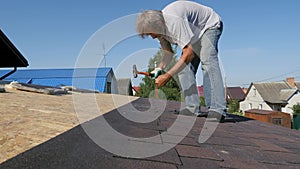 Roofing works. Fixing with nails and a hammer of the roofing material. The camera watches the work of installers.