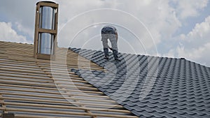 Roofing works. The installer screws the metal tile to the roof crate. Roof construction.