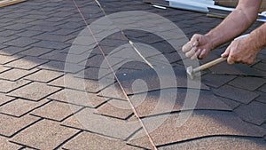 Roofing works. Laying of a soft tile element on the roof ridge and its installation. Installation of the roof to the