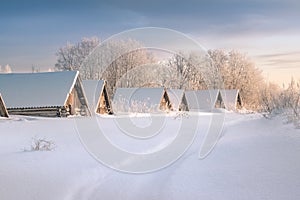 Roofs of cellars over snow in winter field on morning, reparations for winter