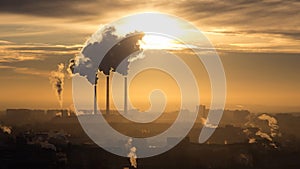 Roofs of city houses during sunrise.Dark smoke coming from the thermal power plant pipe. Time lapse of factory smoke