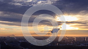 Roofs of city houses during sunrise.Dark smoke coming from the thermal power plant pipe. Time lapse of factory smoke