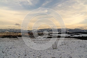 Roofs of houses, trees and fields covered by snow during winter.