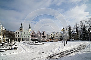 Střechy domů, stromy a pole pokryté sněhem v zimě.