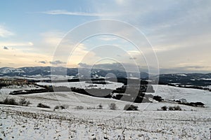 Roofs of houses, trees and fields covered by snow during winter.