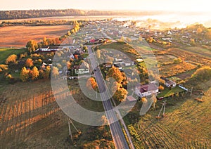 Suburb houses in rural, aerial view. Car driving on road in countryside.