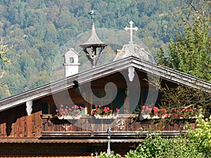 Rooftop of the farmhouse with flowers on the balcony and Christian symbols on the roof