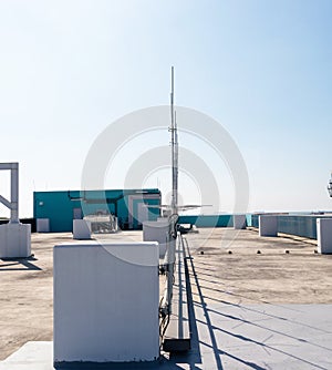 Rooftop small radio television communication tower antenna. Sky with bright sunlight is background.