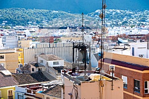 Rooftop View of Denia's Townscape with Bell and Distant Mountains
