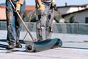 Rooftop waterproofing details. Workers installing bituminous membrane waterproof system insulation photo