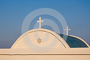 Rooftop of white and blue church with christian cross symbol against blue sky