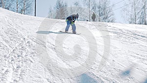 Rookie snowboarder learns to turn on a slope on a sunny winter day at ski resort