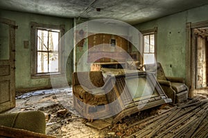 Room of an abandoned house with ruined walls and furniture with an old tv in the middle of the room