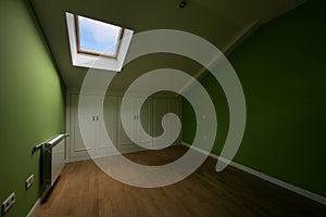 Room in the attic floor with ceilings with skylights and small closets with white doors in the wings