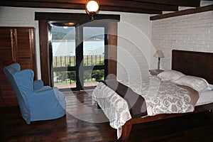 Room with bed, armchair, fireplace and wooden picnic table with a large veranda overlooking the lake of Valle de Bravo in Mexico