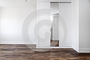 room with chestnut wood flooring, white fitted wardrobes