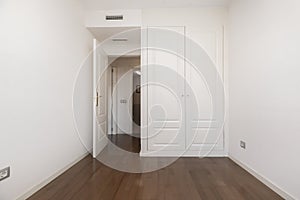 Room with dark parquet floors, fitted wardrobes with white lacquered