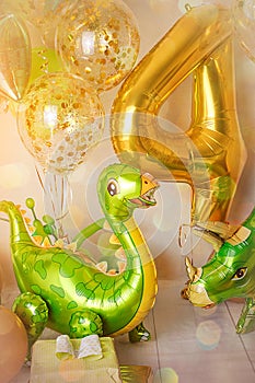 Room decorated for a birthday party with golden, green and yellow baloons, large inflatable number 4, Dinosaur baloons