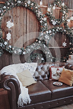 The room is decorated for the New Year. Christmas wreaths, white blanket and pillows on the couch.