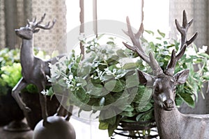 room decoration with deers and flowers on the table against the backdrop of curtain and large window, selective focus